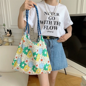 Detailed shot of floral canvas tote bag featuring yellow daisies and blue woven handles
