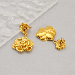 Detail of 18K gold plated stainless steel double rose flower earrings on textured background