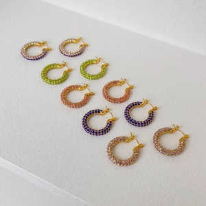 Detailed row of gold hoop earrings set with colorful zircon stones in five pastel shades