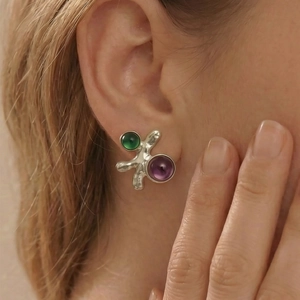 Boucles d'oreilles argentées ondulées avec cabochons violets et verts sur un mannequin