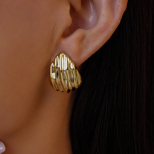 Gros plan d'une boucle d'oreille dorée géométrique texturée sur un mannequin élégant