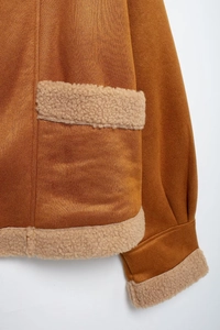 Detail der braunen Wildlederjacke mit beigen Lammfell-Taschen und Manschetten