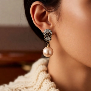 Macro view of vintage gold earrings with black enamel, rhinestones and large pearl pendant