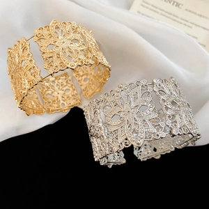 Détail des bracelets ajourés fleurs en métal doré et argenté sur tissu satiné