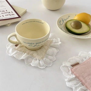 Close-up of elegant beige cotton coasters with wide lace borders for afternoon tea décor