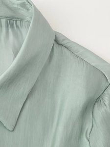 Detail of sage green silk blouse collar showing luxury texture and stitching