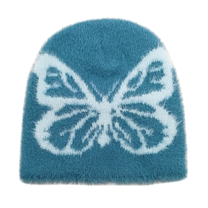 Close-up of soft blue plush beanie featuring a large white knitted butterfly pattern