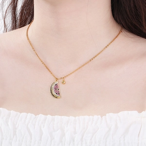 Gold watermelon pendant necklace with pink crystals on model's neck for summer style