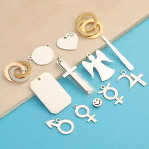 Flat lay of diverse stainless steel pendants in gold, silver, and rose gold finishes