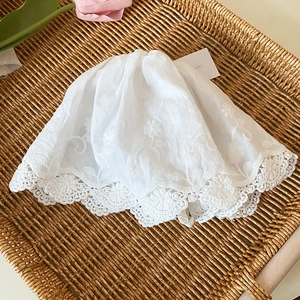 Détail de la broderie florale sur un chouchou en dentelle blanche dans un panier