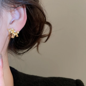 Detail of a gold unicorn stud earring with clear gems on a model for a luxury look