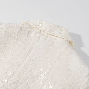 Dettaglio macro del colletto del blazer bianco con paillettes e trama lucida definita