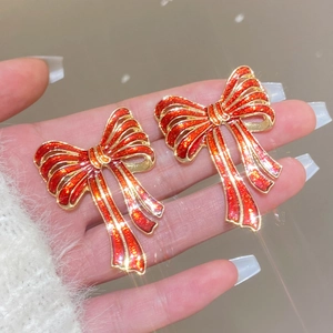 Sparkly red bow earrings with gold trim held by hand for Christmas fashion