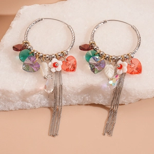 Detail of silver twisted hoop earrings with heart crystals, beads and metal tassels