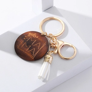 Detail of walnut wood keychain with MAMA engraving, golden lobster clasp, and white tassel