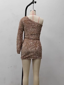 Detail of champagne gold sequin dress with one-shoulder long sleeve and irregular hem