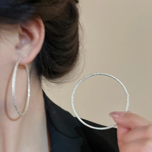 Close-up of textured silver hoop earrings worn by a model for a chic minimalist style