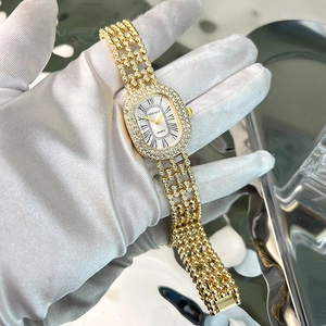 Detailed macro view of gold-tone oval watch with diamond accents and Roman numerals