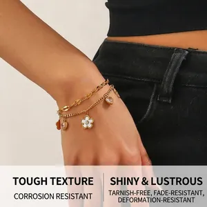 Detail of double-layer gold chain bracelet with white flower and heart crystal charms