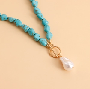 Detail of turquoise bead necklace with golden OT clasp and a large baroque pearl pendant