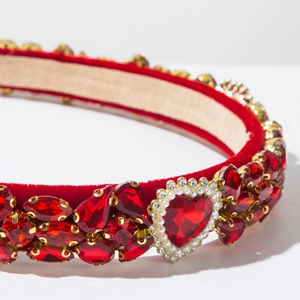 Detail van rode fluwelen haarband met hartvormige stras en barokke parels