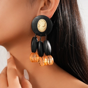 Close-up of vintage style earring featuring a gold portrait relief and acrylic beads