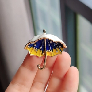 Detailed close-up of a blue starry sky umbrella brooch with gold plating and rhinestones