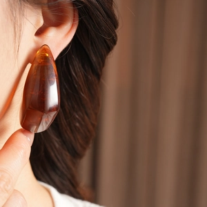 Close-up of a vintage amber resin teardrop earring with irregular geometric texture
