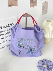 Detail of purple embroidery tote bag with red rope handles and matching hair scrunchie