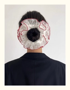 Détail du chouchou floral géant avec bordure en dentelle rouge sur blazer noir