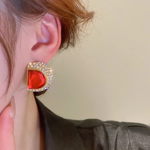Gros plan d'une boucle d'oreille de luxe en forme de D avec une pierre rouge
