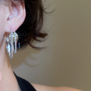 Gros plan de boucles d'oreilles argentées multicouches avec zircons sur modèle