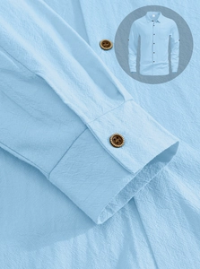 Detail of light blue linen shirt featuring premium wood buttons and slub fabric texture
