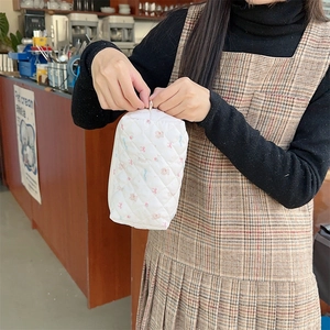 Quilted cosmetic bag featuring cute bear patterns held by a hand to show portable size