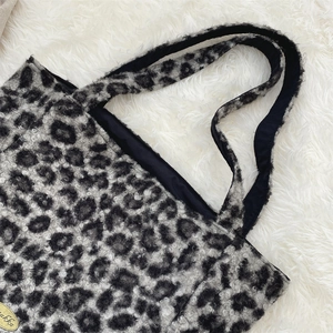 Close-up of leopard print fleece tote bag with soft texture and golden metal logo tag