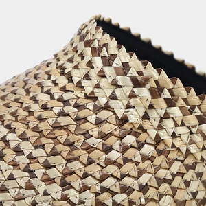 Macro view of woven straw sun hat featuring two-tone brown and beige diagonal patterns