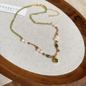 Detail of 18k gold plated necklace with green beads, freshwater pearls and gemstone pendant