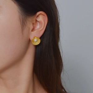 Boucles d'oreilles coquillage dorées avec perle centrale et texture rayonnante