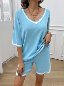 Detail view of blue knit two-piece set featuring V-neck top with white trim and shorts