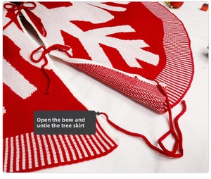 Close-up of red and white knitted Christmas tree skirt with snowflake patterns and bow tie