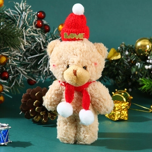 Close-up of cute plush teddy bear with a red knitted hat and LOVE gold lettering