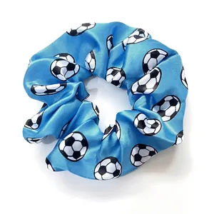 Detailed view of bright blue satin scrunchie featuring classic black and white soccer prints