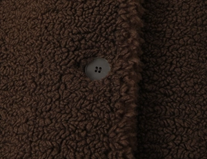 Close-up of deep brown teddy fleece fabric texture with a matching four-hole button detail