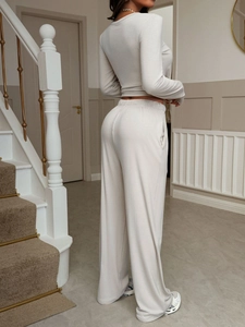 Back view of a woman wearing a casual beige long-sleeve shirt and wide-leg pants set