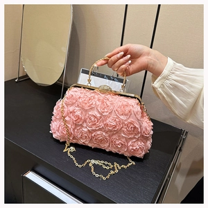Close-up of pink 3D rose evening bag with golden metal handle and chain strap