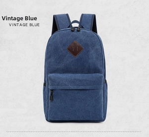 Front view of vintage blue canvas backpack featuring a brown leather patch and dual zippers