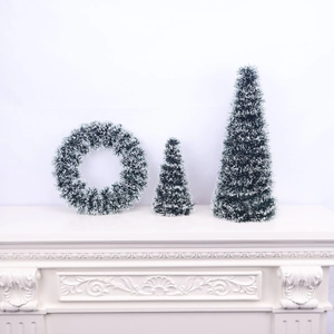 Frosted Christmas wreath and mini trees displayed on a white mantel with snow-tipped leaves