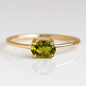 Macro shot of an oval olive green gemstone ring with a gold-plated four-prong setting