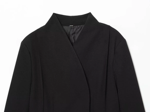 Détail d'un blazer noir sans col montrant la texture du tissu de qualité et la doublure