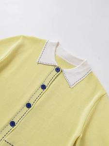 Close-up of yellow knit cardigan featuring a white polo collar and navy buttons